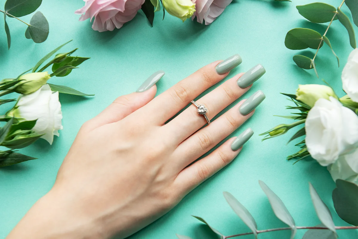 manicured hand with long, light green nails