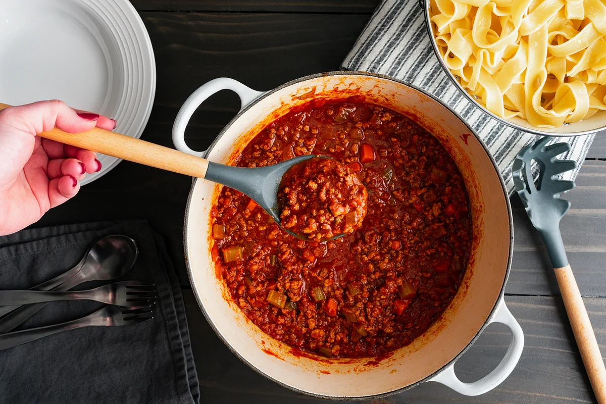 Hand Holding a Serving Spoon of Authentic Bolognese Sauce