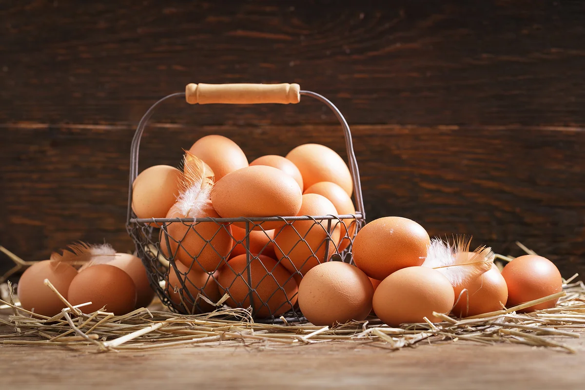 basket of fresh chicken eggs on a wooden background