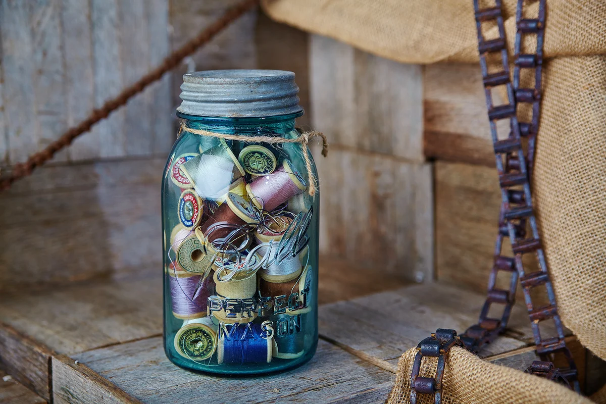 Vintage Sewing Essentials in Blue Mason Jar on Rustic Wooden Surface