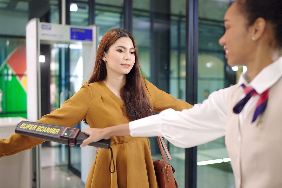 Security agent at airport check in gate with metal detector
