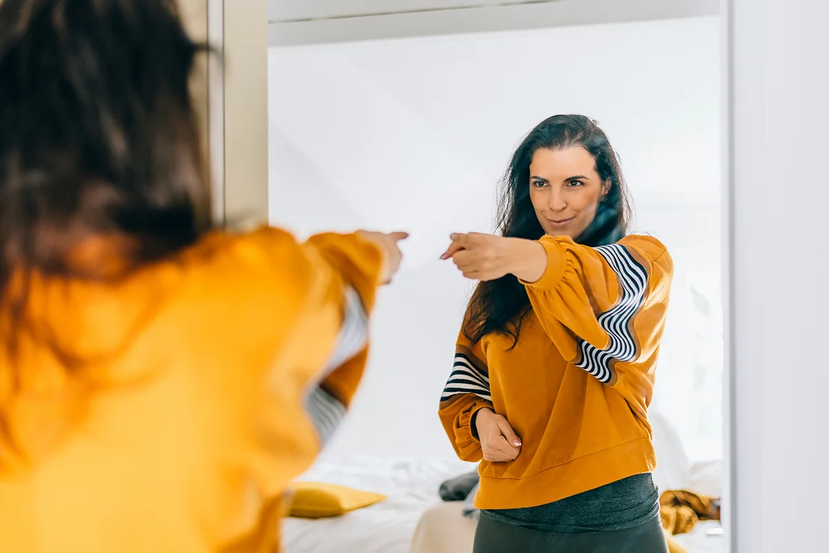 Self confident single woman pointing finger at her reflection in mirror