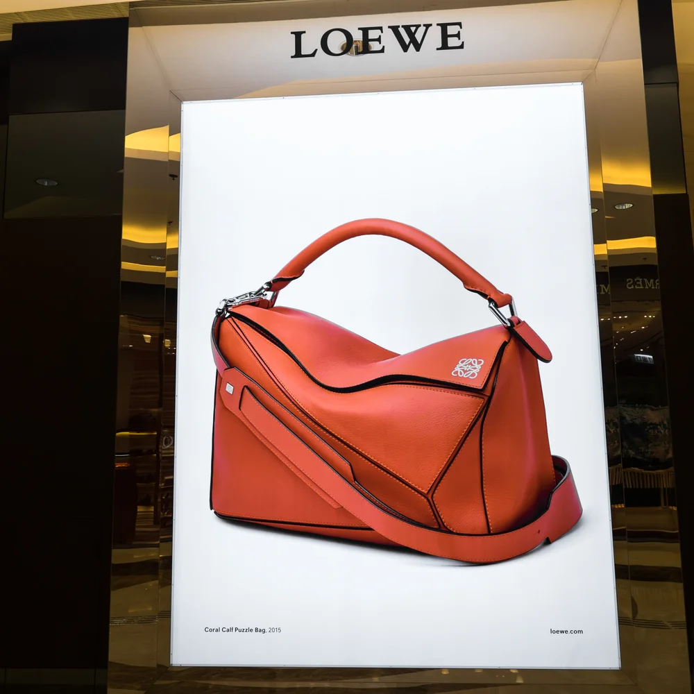 HONG KONG - 22 JAN, 2015: Loewe boutique display window with Puzzle Small Bag advertising photography. Spanish luxury fashion house based in Madrid produces clothes, fragrances and accessories