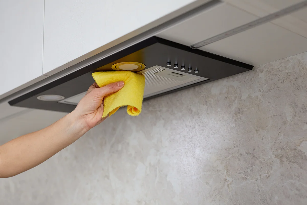 Woman hand cleaning range hood in the kitchen