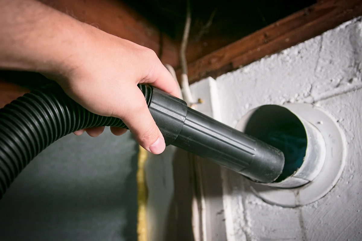 Vacuum cleaning out home dryer vent to remove built up lint hazard.