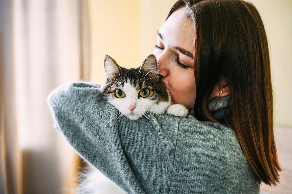 Woman at home holding her cat in hands
