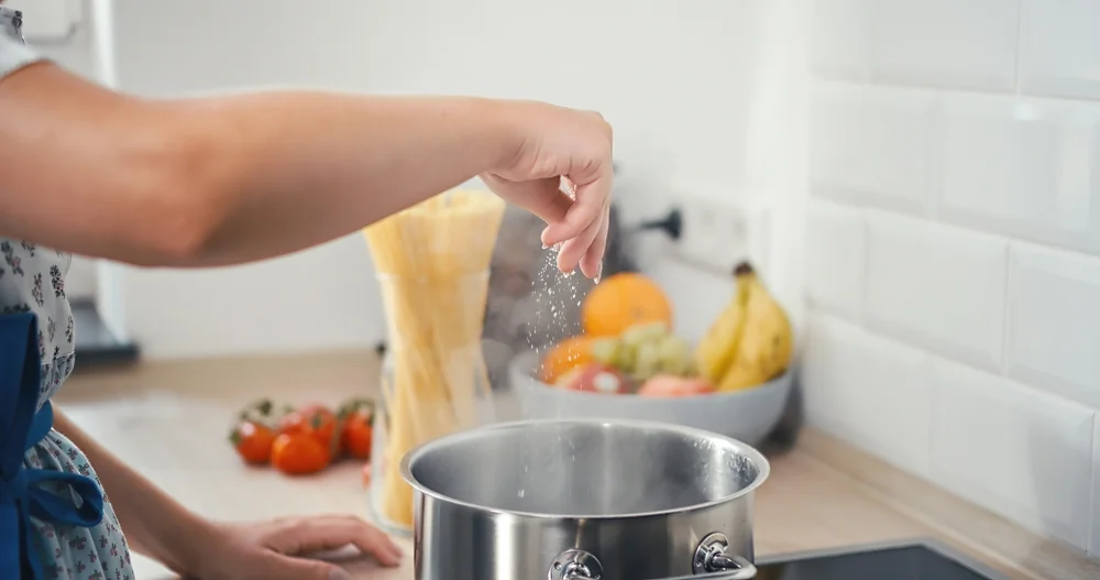 woman salting pasta water
