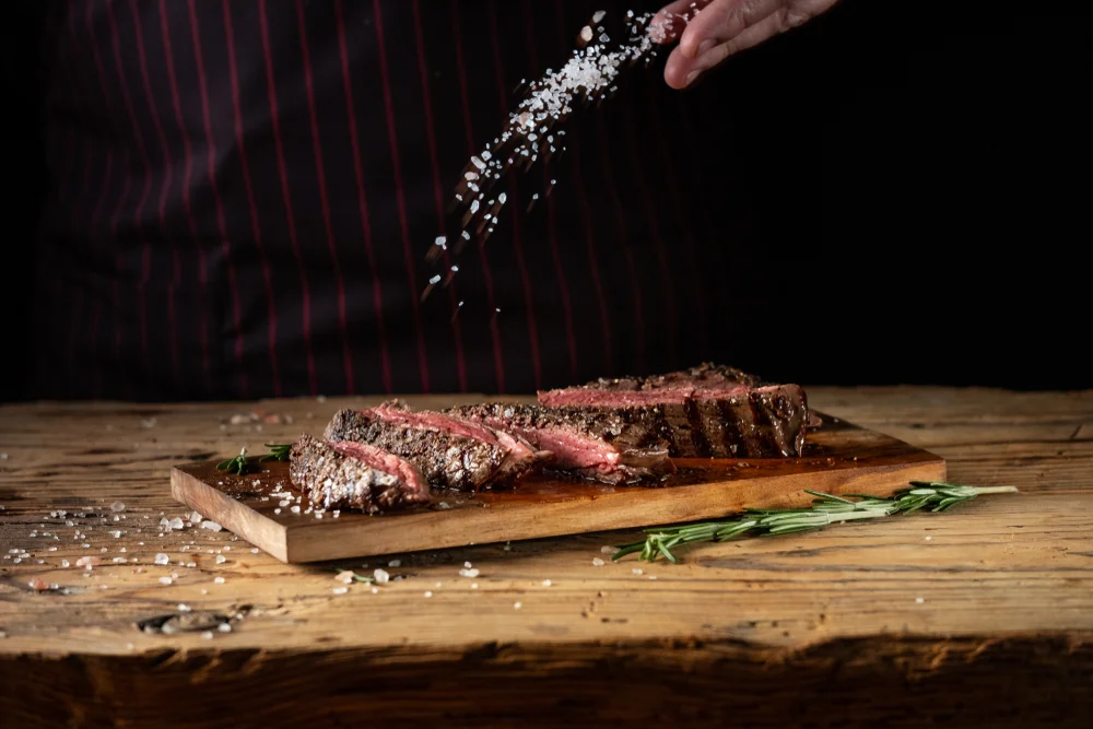 closeup of man's hand salting meat