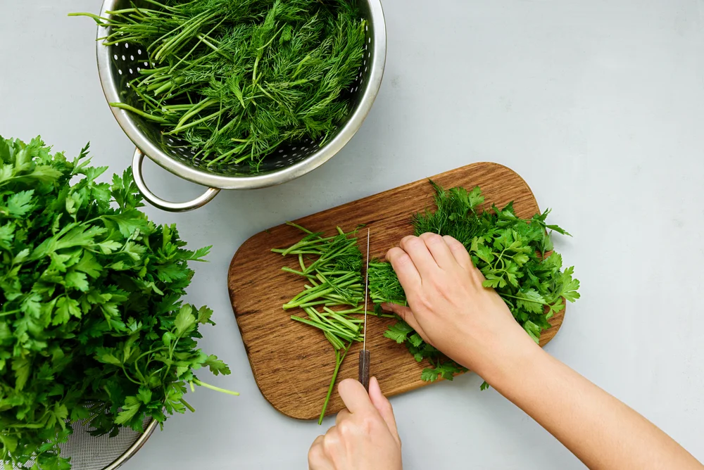 Overhead shot of woman's hands chopping fresh herbs