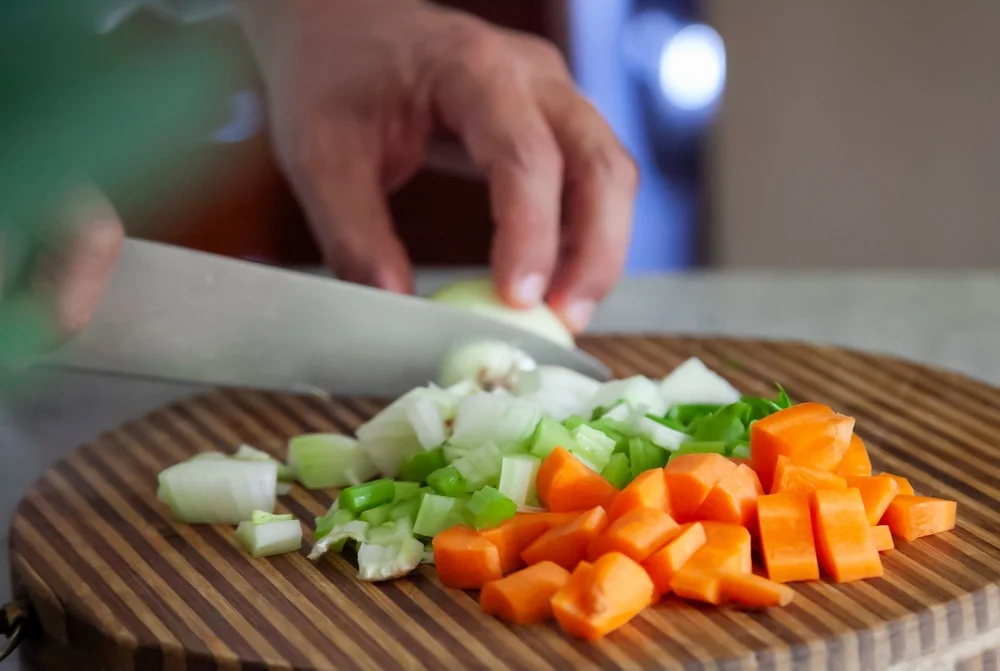 closeup of hands chopping mirepoix
