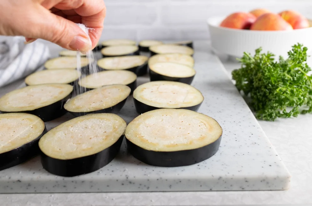 closeup of woman's hand salting eggplant
