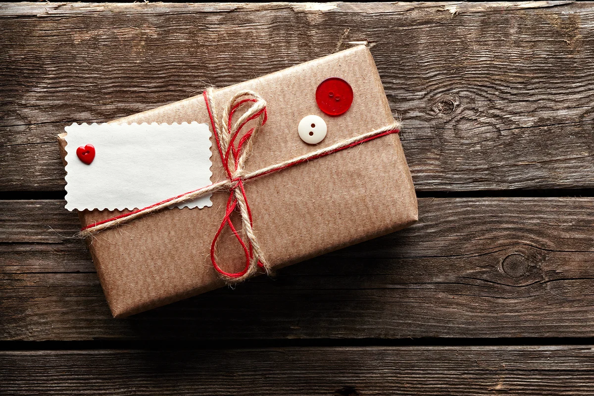Vintage gift box with blank gift tag on old wooden background.