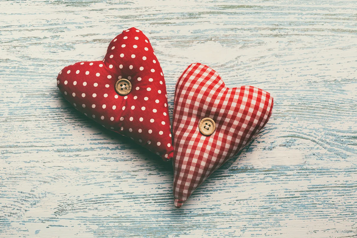 Two fabric hearts on wooden background