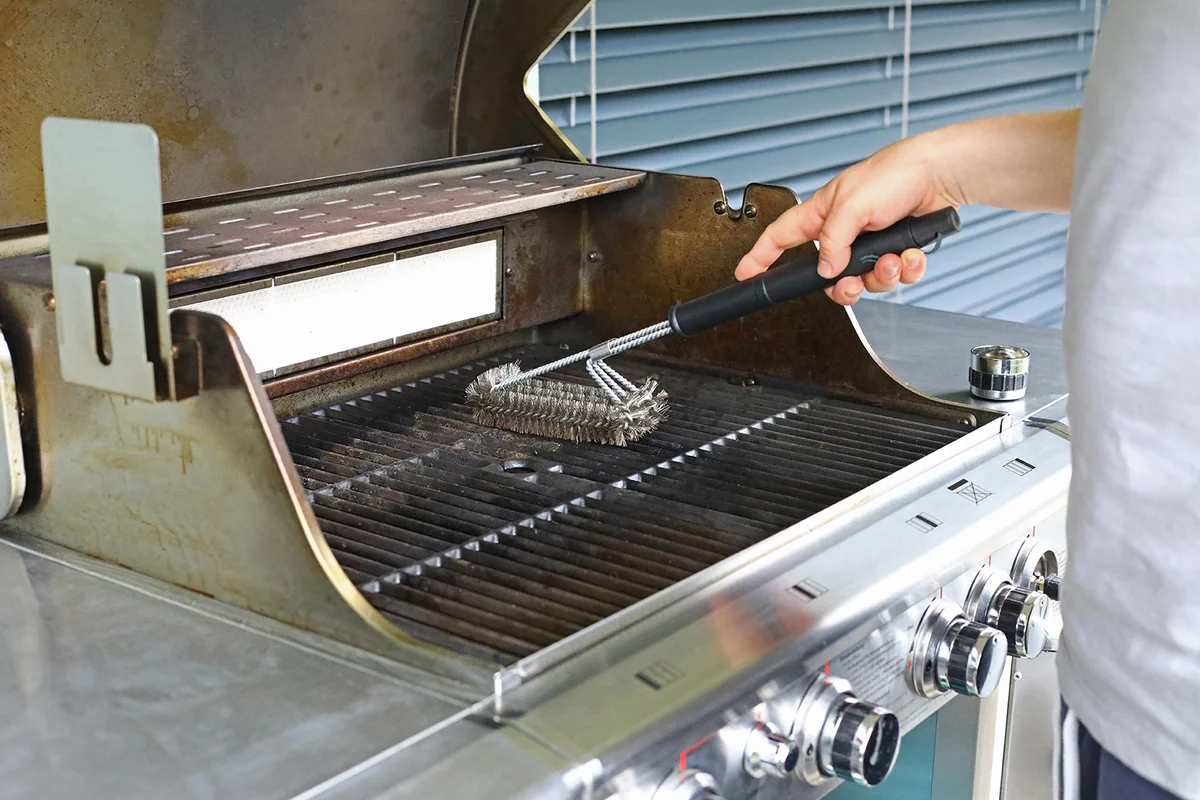 Man cleaning home grill after eating