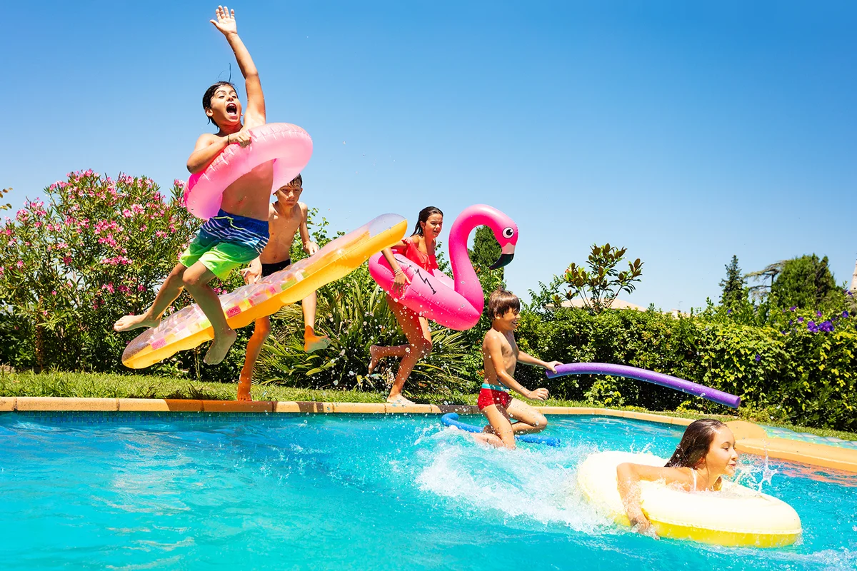 Happy friends jumping in pool on the vacations