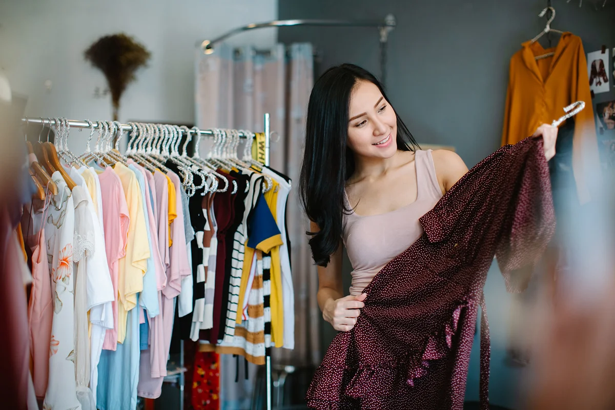 woman choosing new clothes in shop and smiling