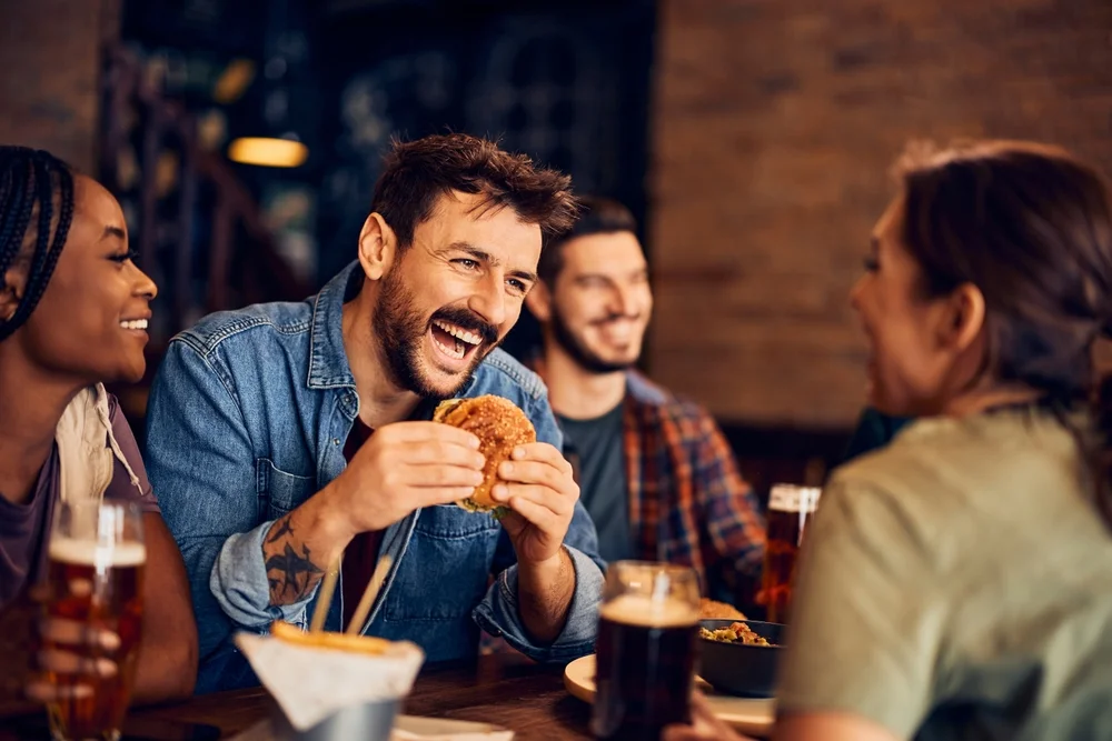 Man eating a burger with friends in a restaurant