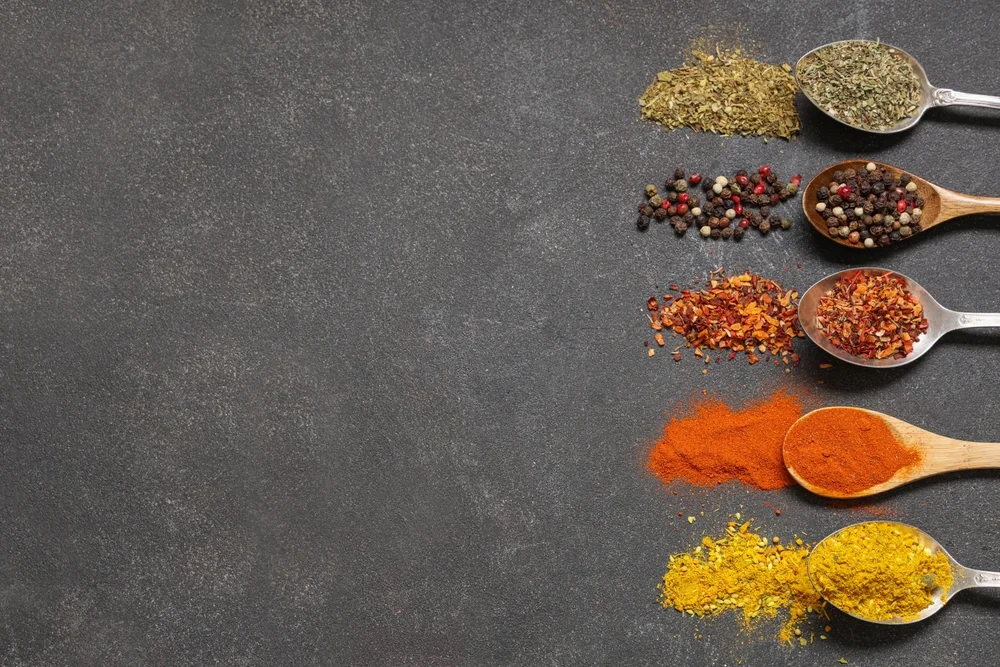 spoons of dried spices on a slate background