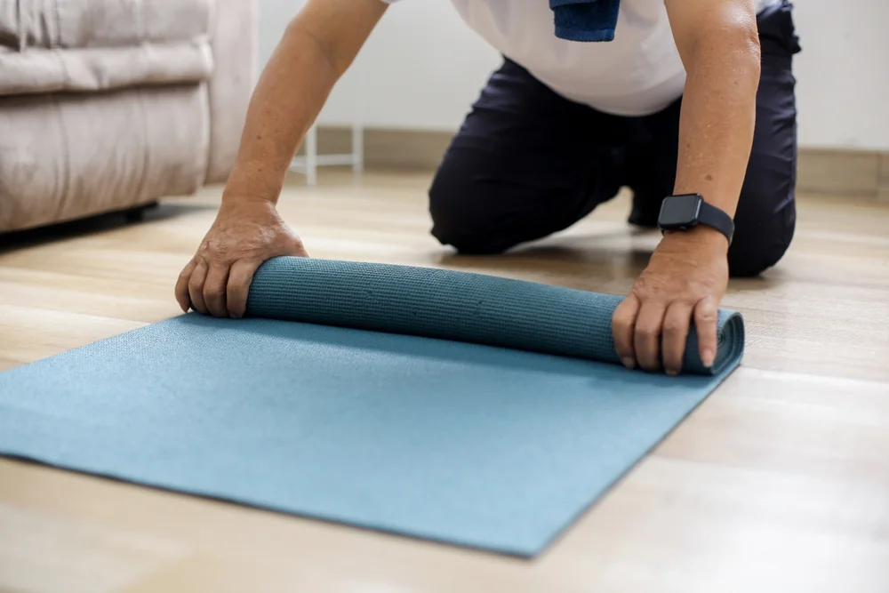man rolling up a yoga mat