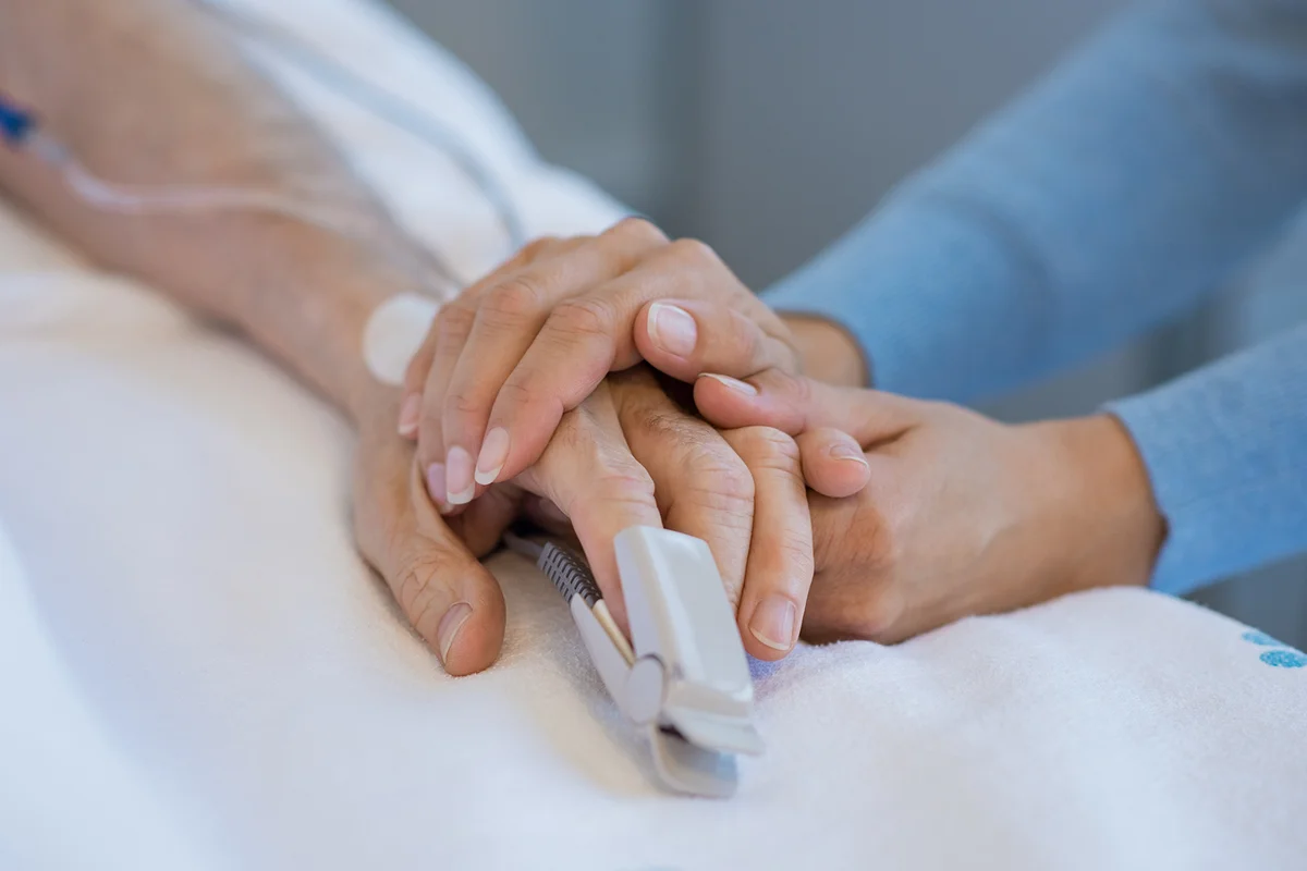 Daughter holding the hand of an elderly father