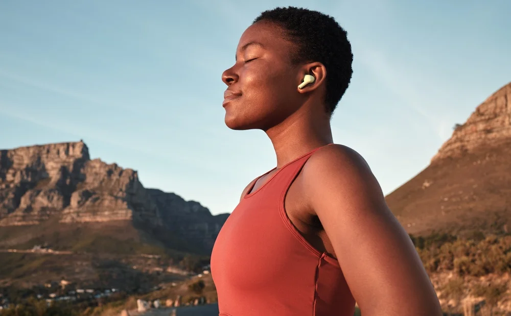 fit woman with earbuds deep breathing outdoors