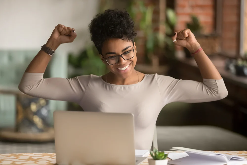 happy woman celebrating at her laptop