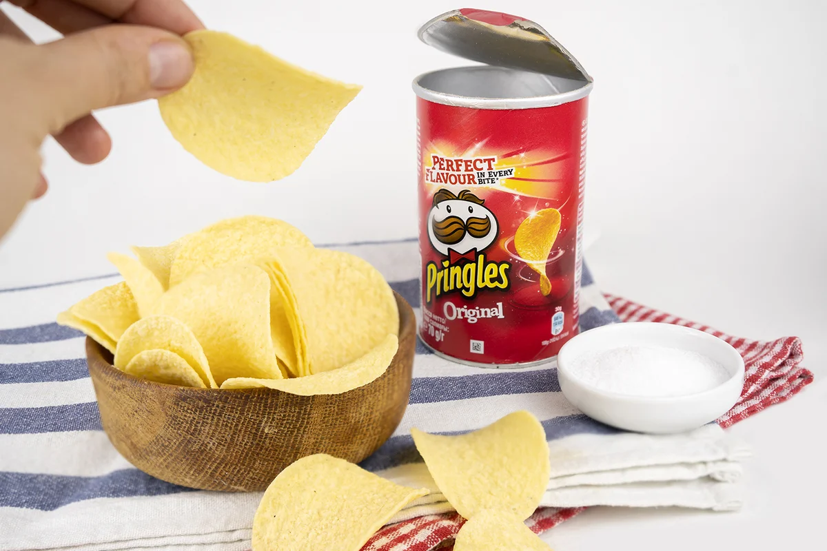 Pringles original chips box with a wooden bowl full of salty chips