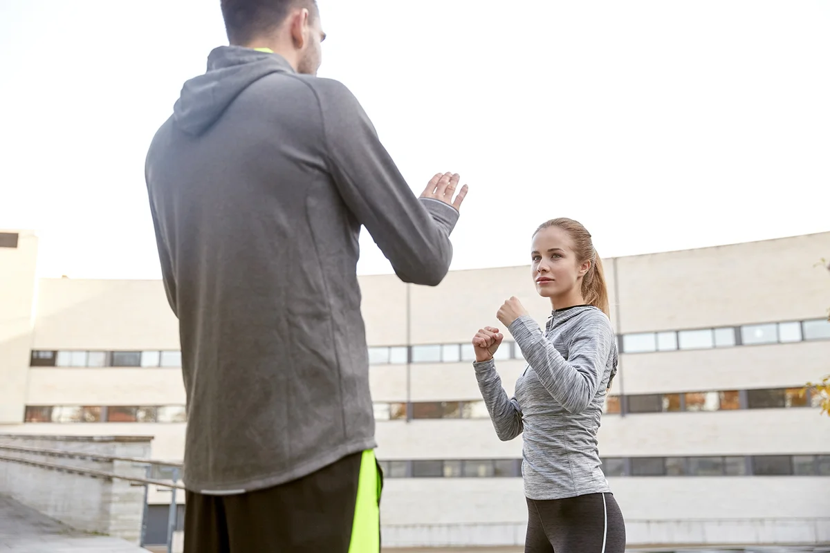 young woman with trainer working out self defense