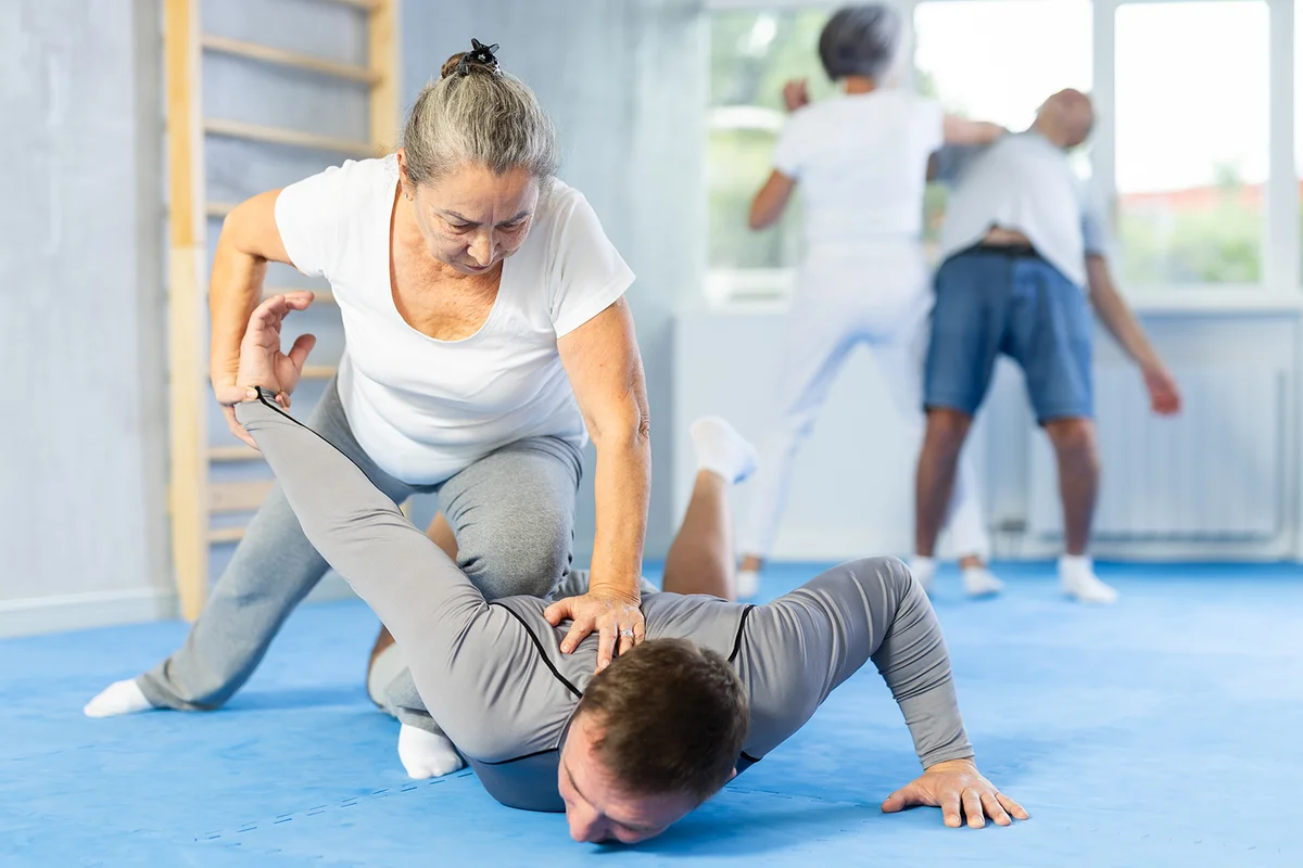 Aggressive old woman twisting her opponent's arm during self-defense classes