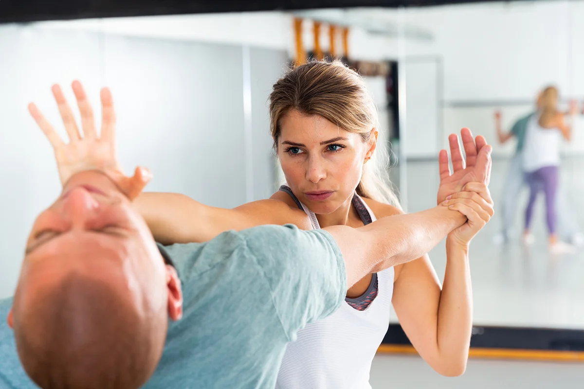 Concentrated girl practicing effective self defence techniques with coach