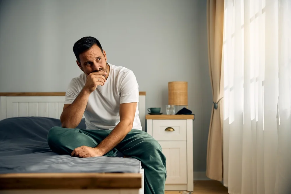 worried man sitting on bed