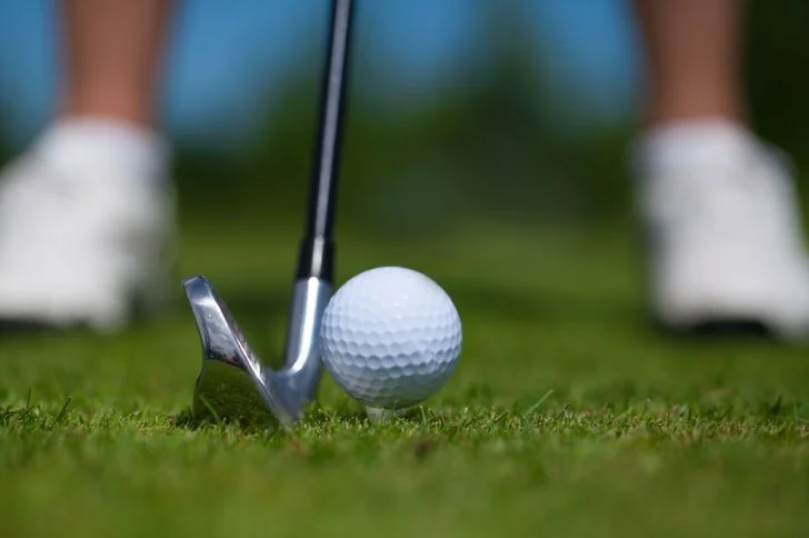 golfer standing over a tee shot with iron