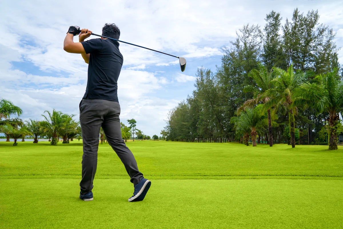 Golfer swinging driver on course