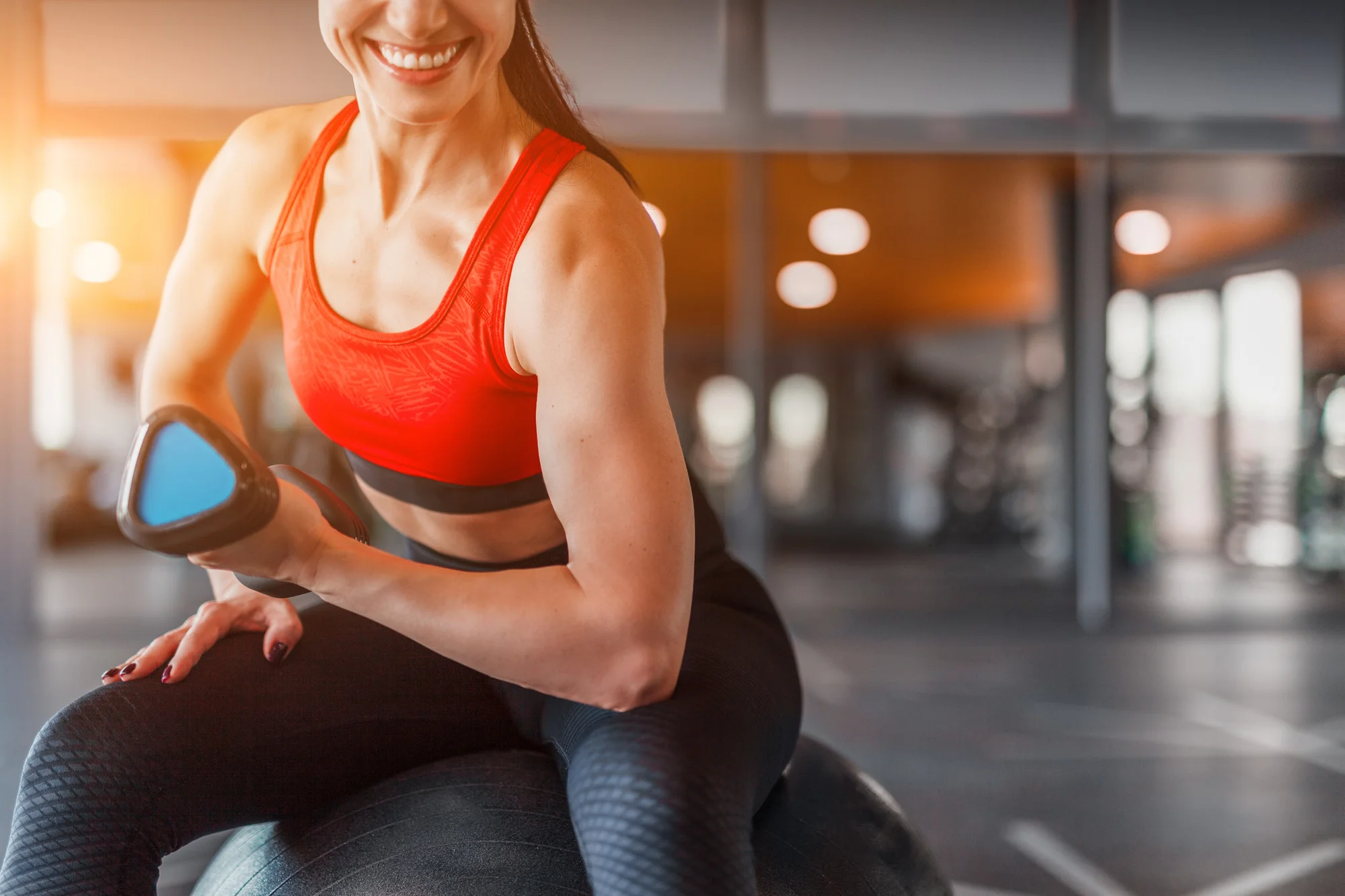 Woman doing bicep curl on a medicine ball