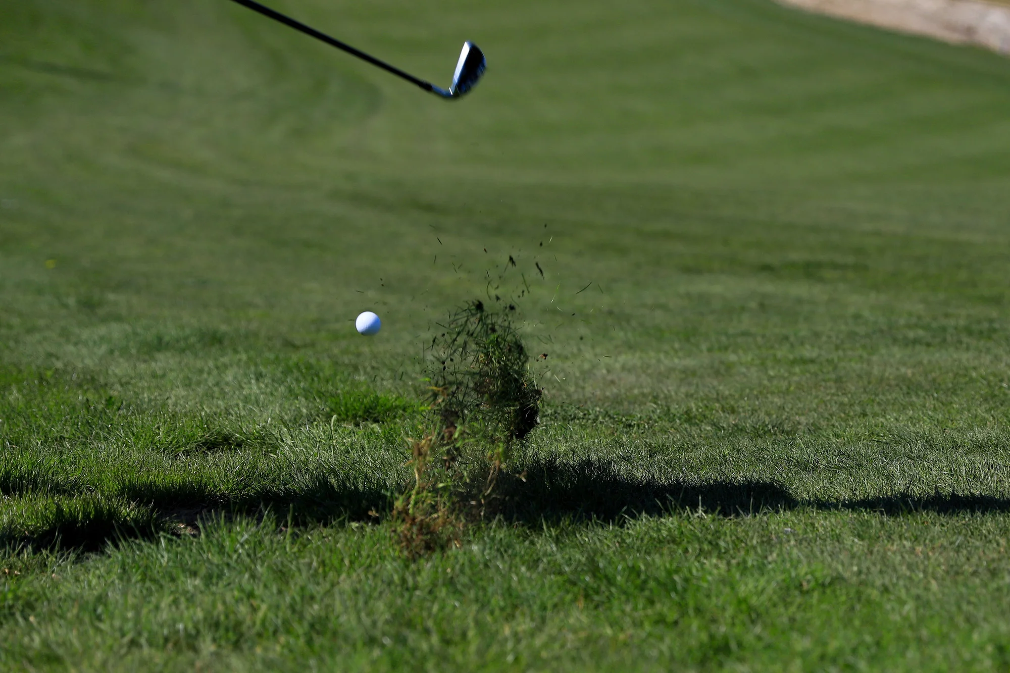 Golfer hitting a shot off a downhill lie