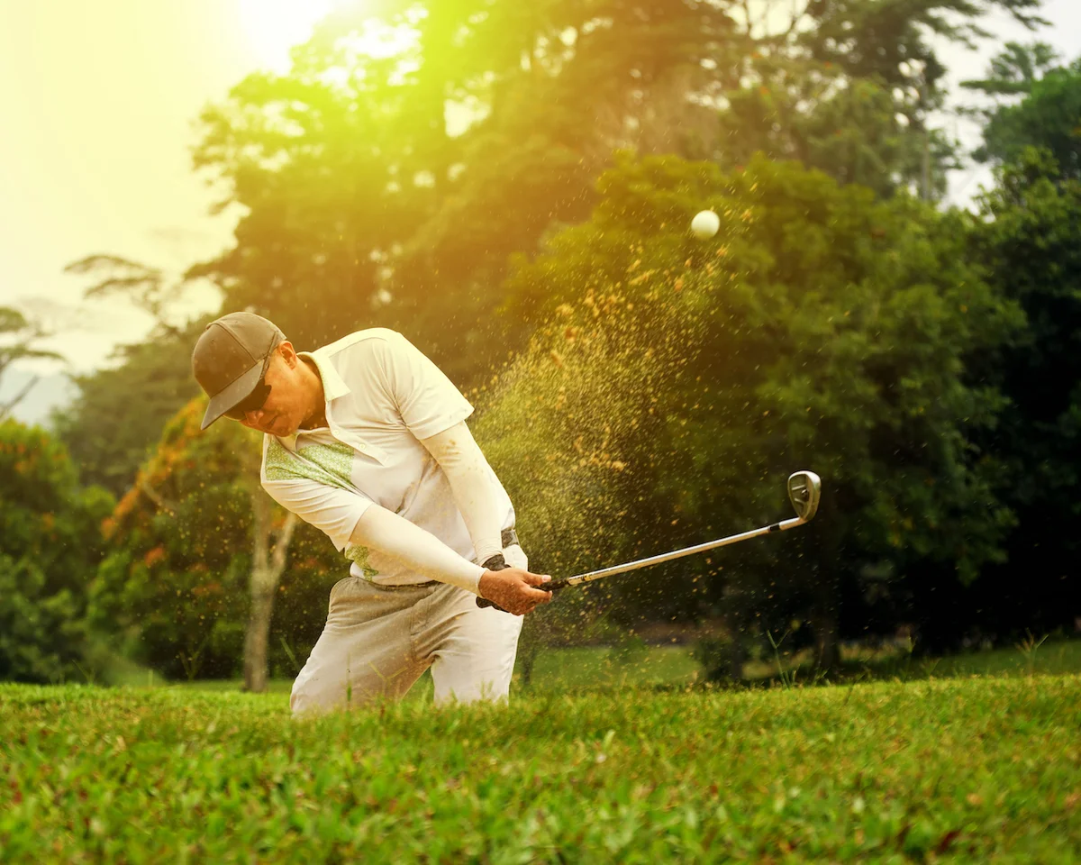 Golfer hitting ball out sand trap