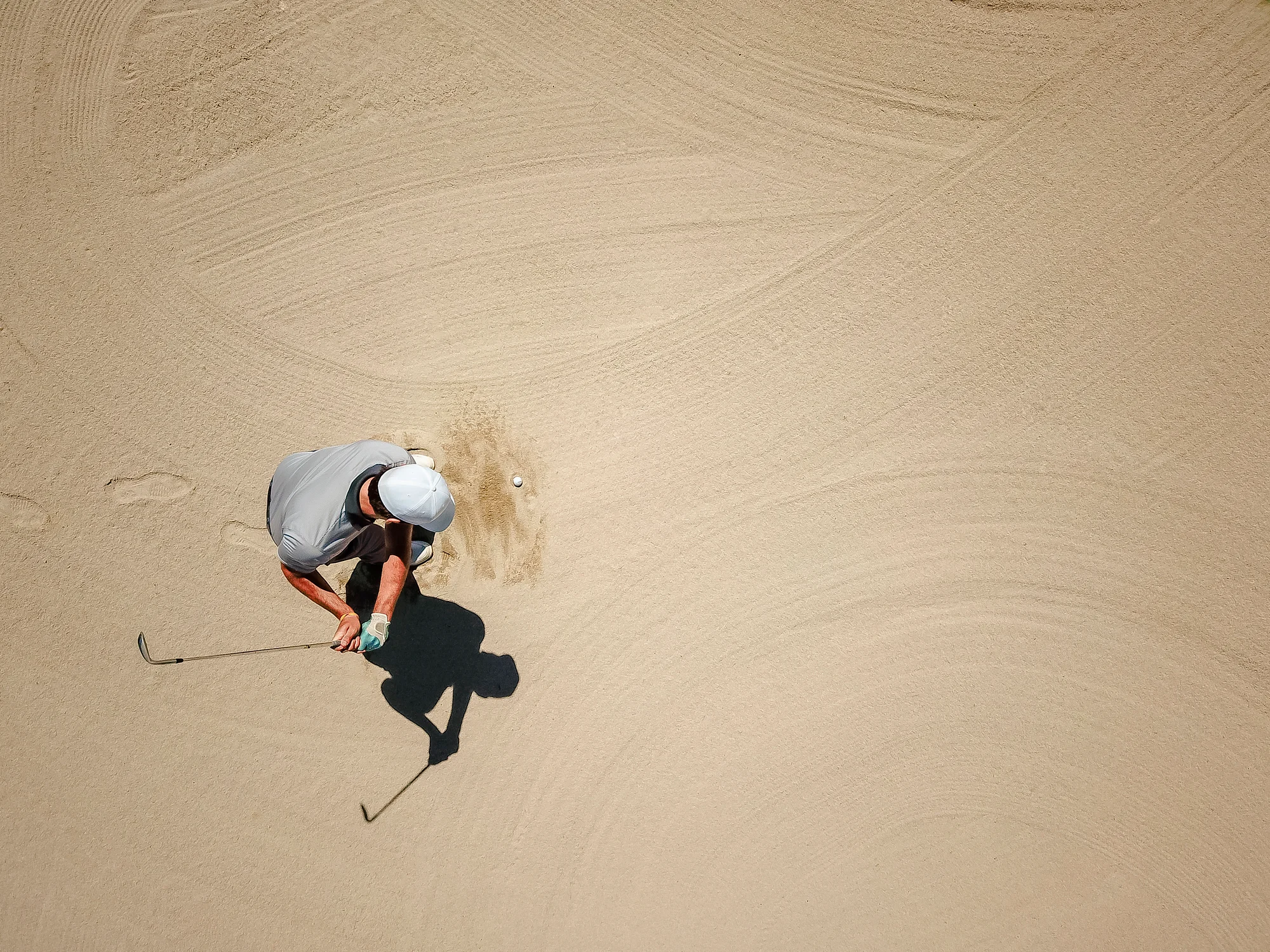 Man plays a golf shot from a fairway bunker