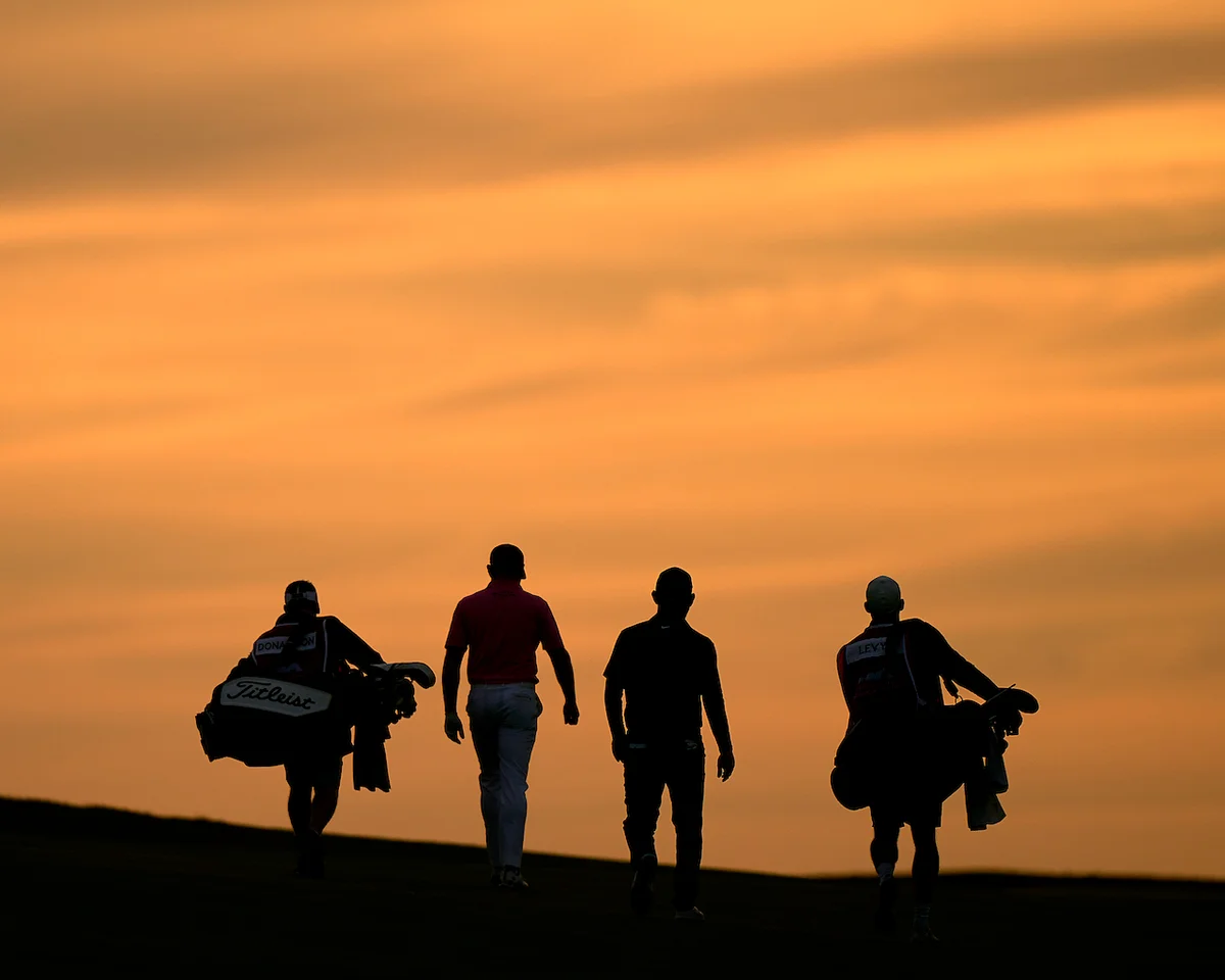 Golfers and caddies walking at twilight