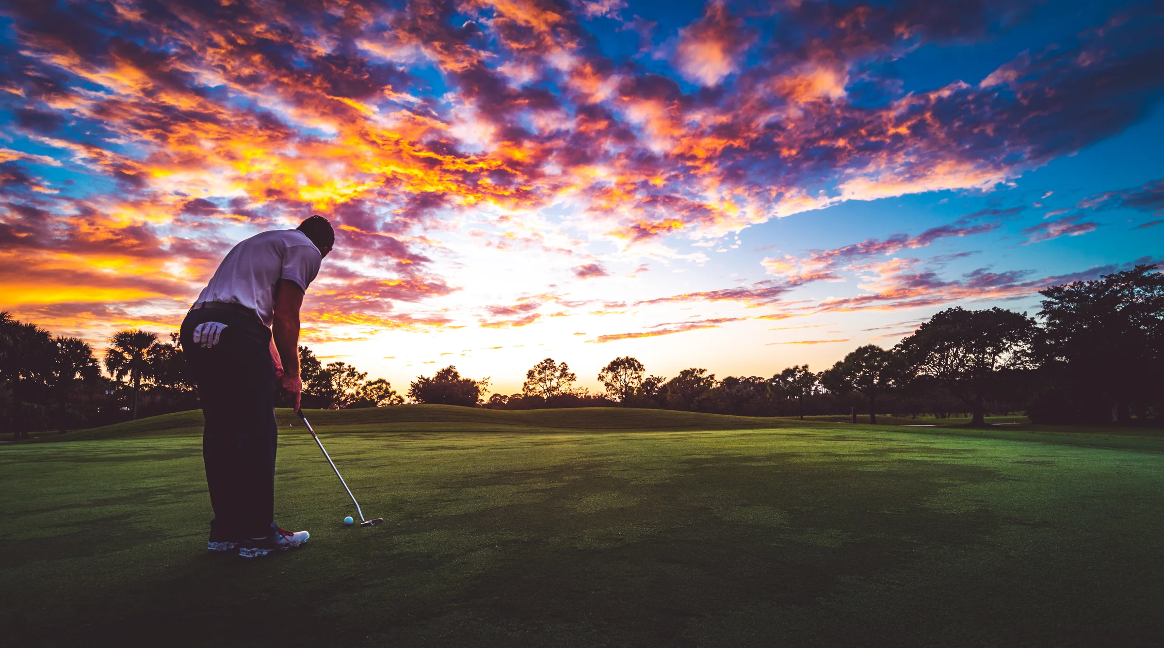 Man putts at sunset