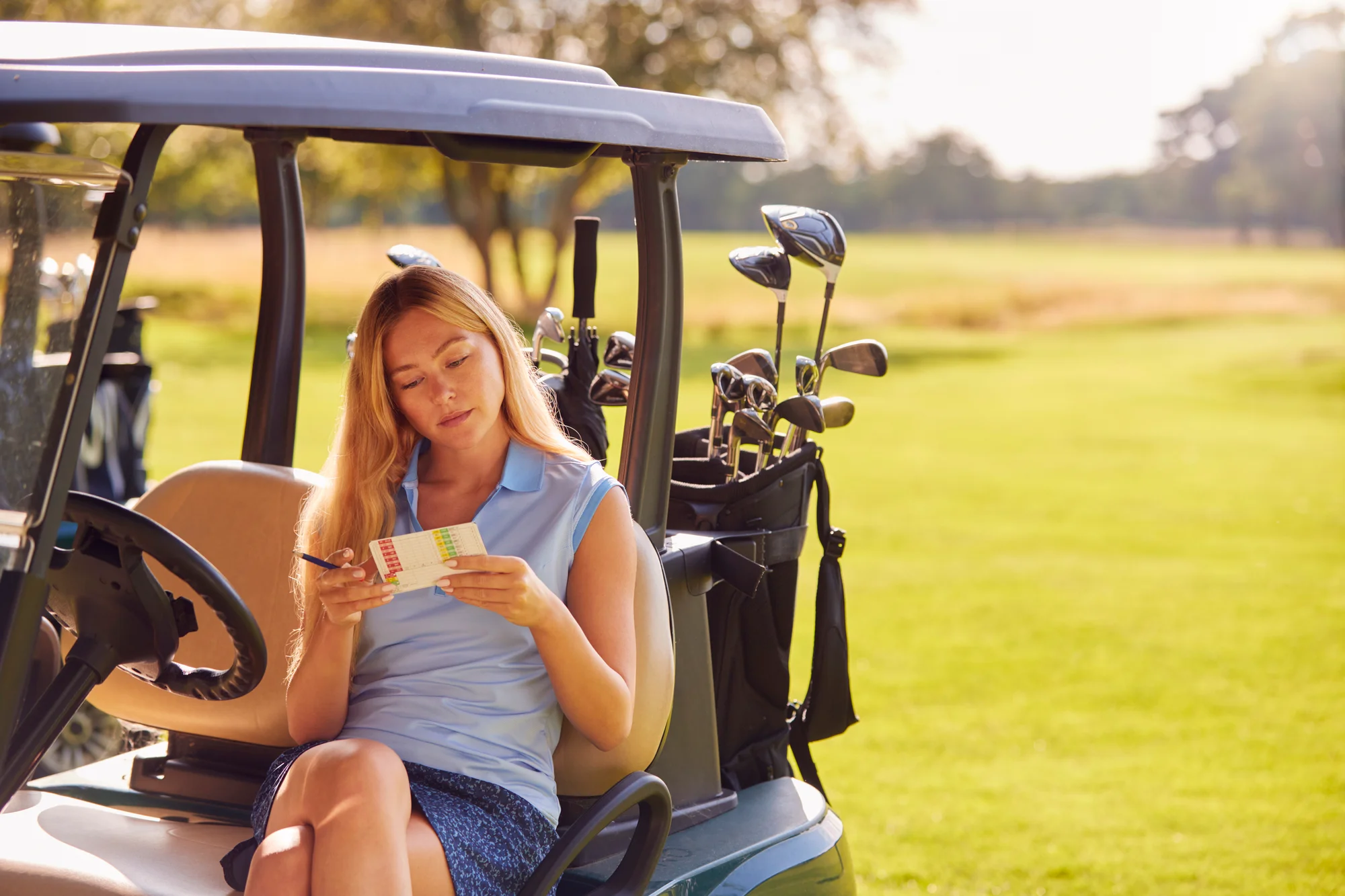 Woman studying the scorecard from her golf cart