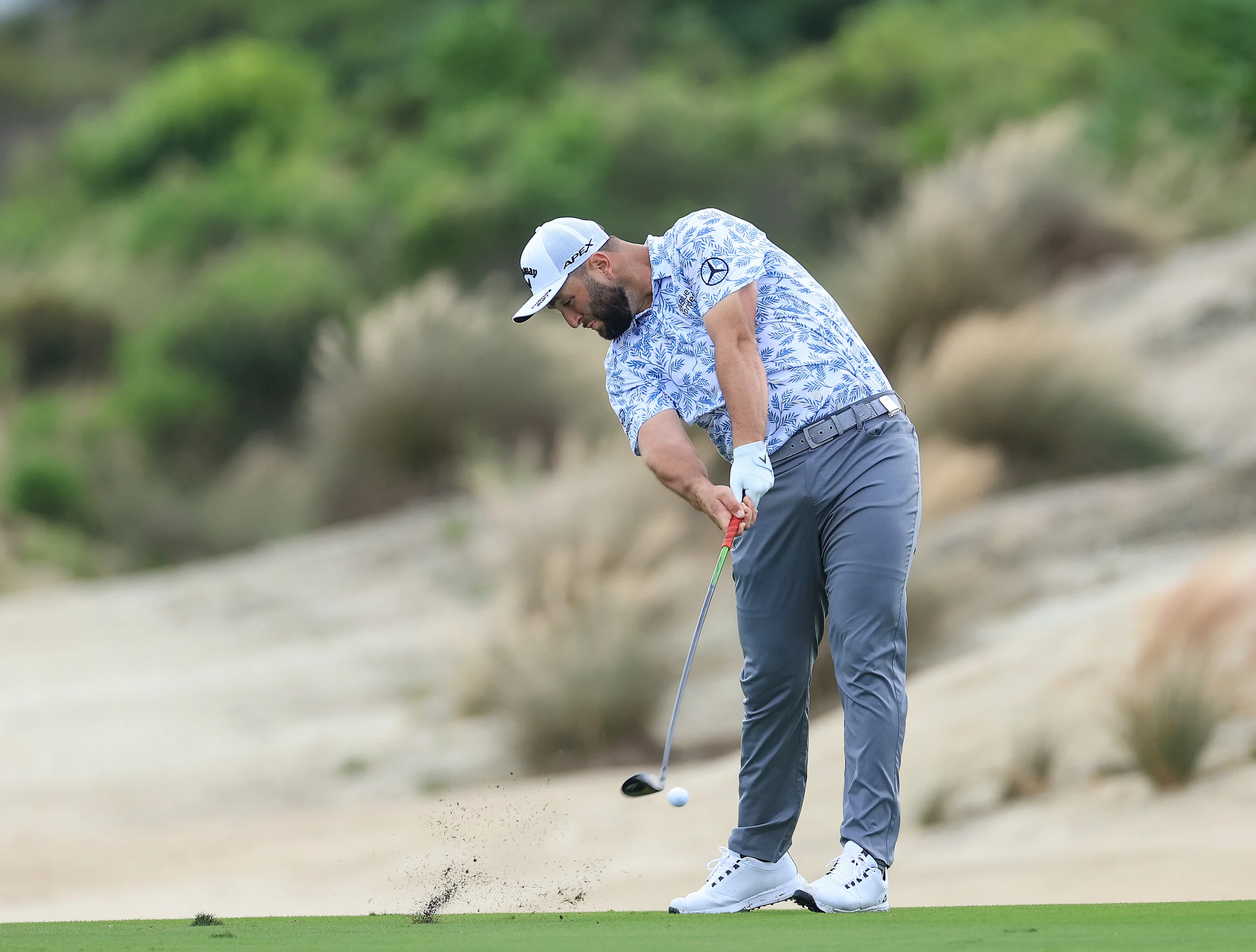 Jon Rahm hitting a hybrid golf club