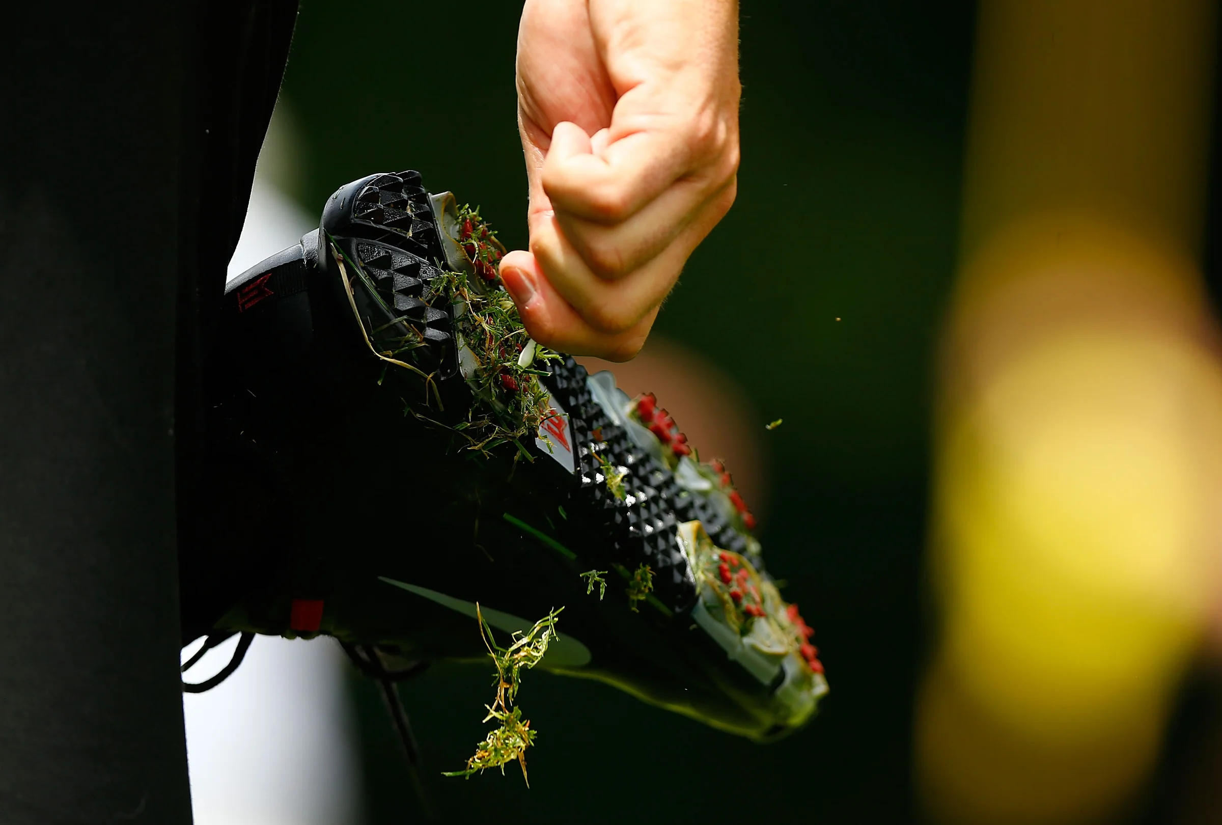 Golfer scrapes grass off shoes