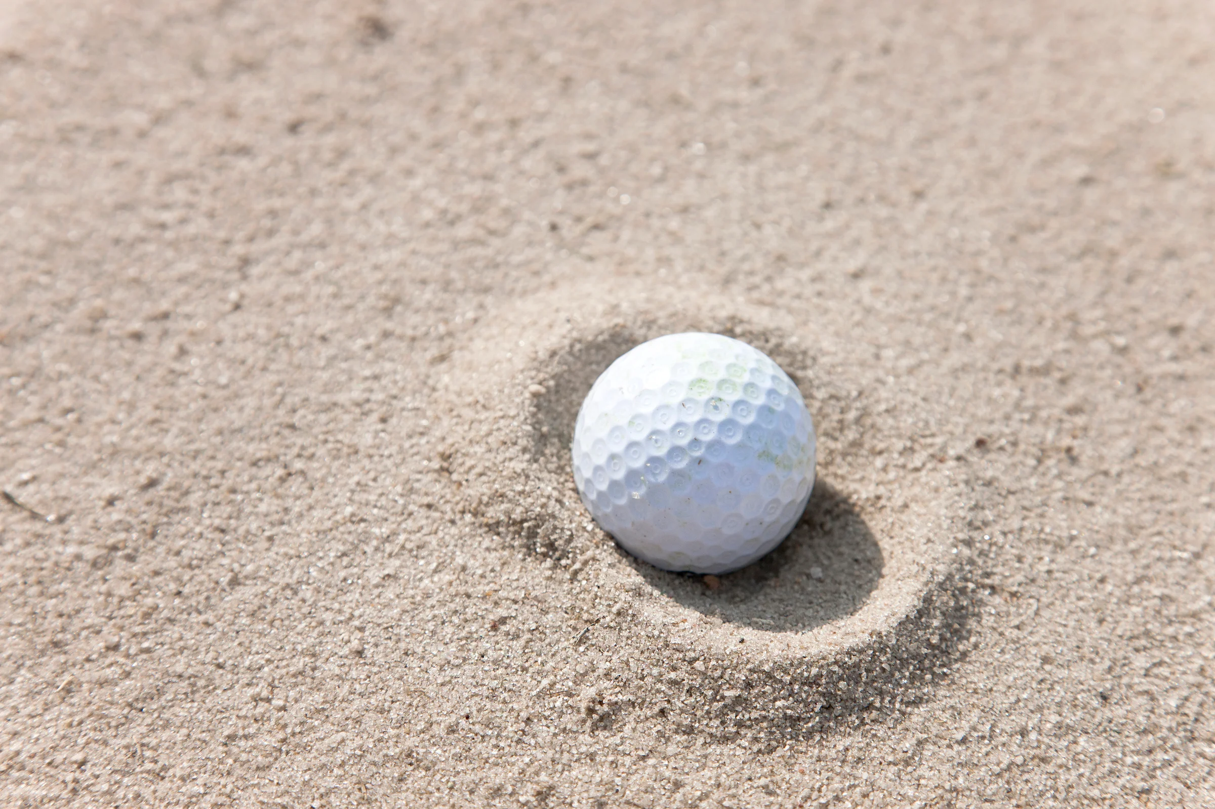 Golf ball in a fried egg lie in the bunker