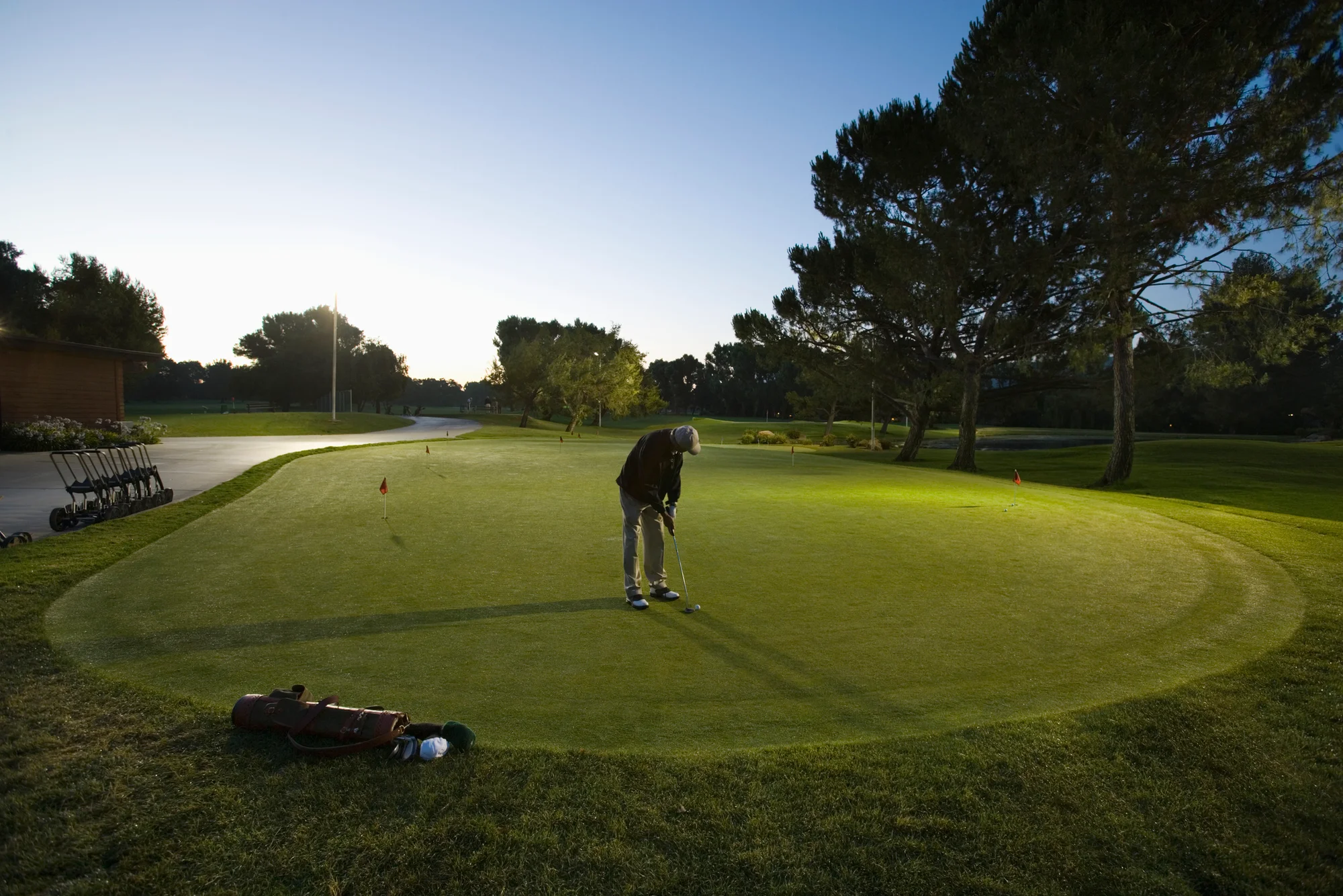Golfer practicing putting distance control at dawn