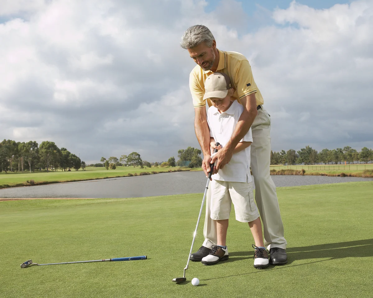 Man helping grandson with putter