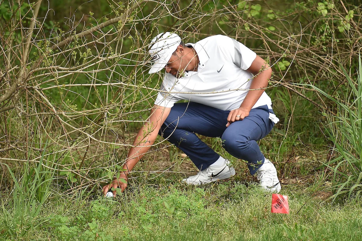 Tony Finau grabbing ball in brush