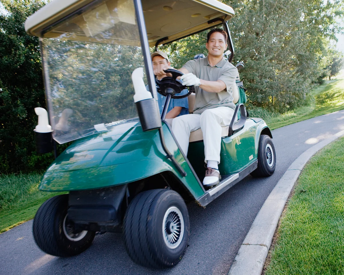 Man driving golf cart on path