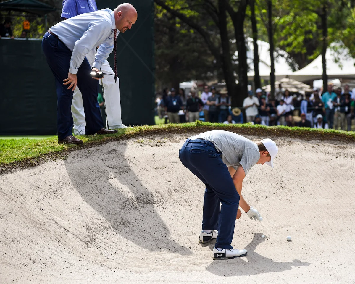 Jordan Spieth examines ball in bunker