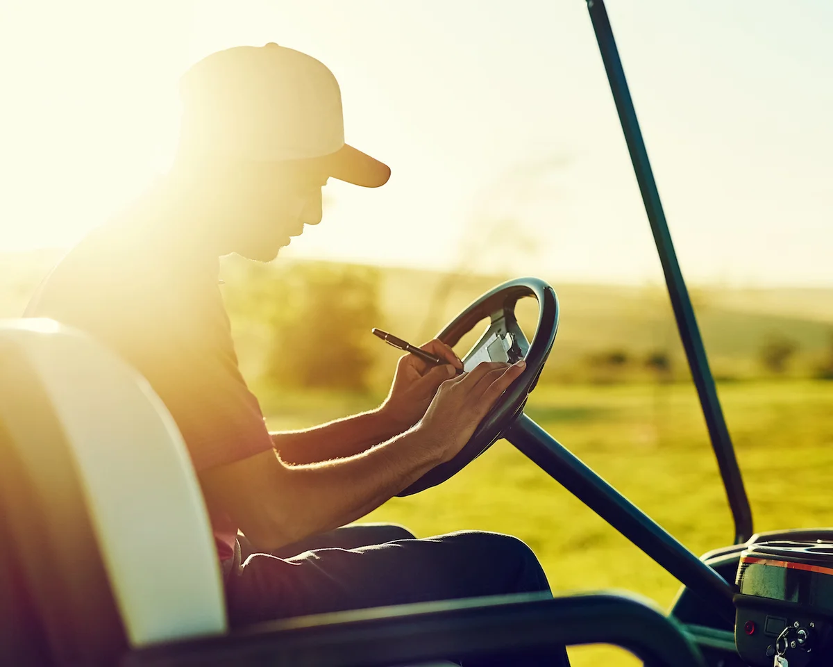 Golfer writing on scorecard in cart