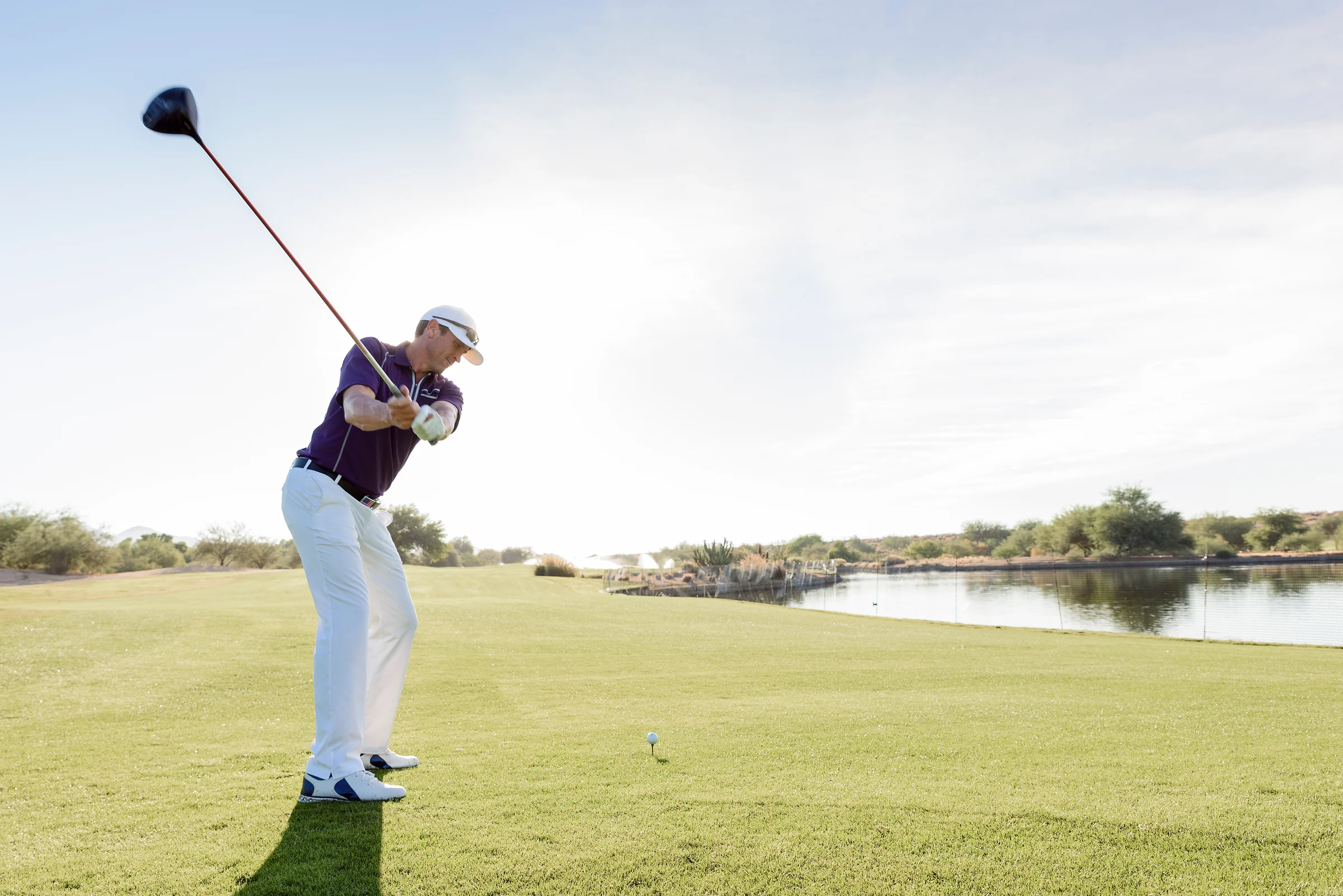 Man hitting driver confidently despite water hazard in play